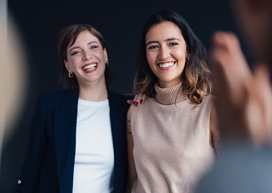 Two women smiling dressed in work attire