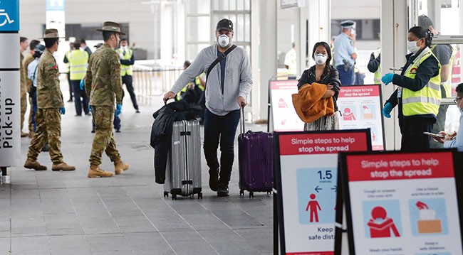 Expats migration masked travellers in airport Masked travellers walk through airport