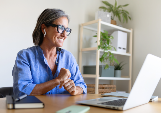 Person interacting with laptop from a home office workspace.