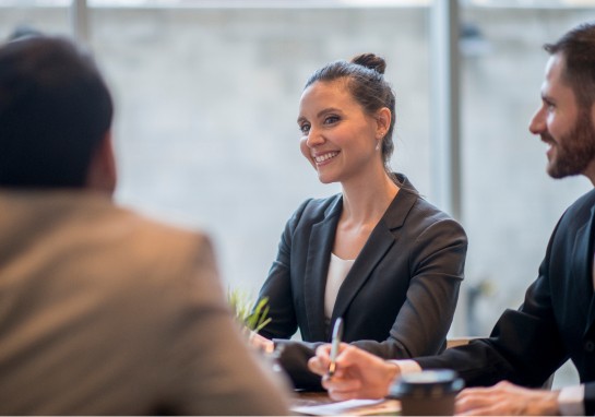 A woman in a business suit engages in conversation with two colleagues in a professional setting.