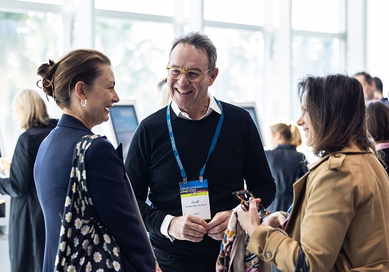 Three individuals engaged in conversation at a event, exchanging ideas and smiles.