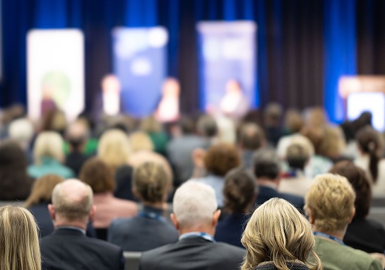 A bustling conference room filled with a diverse crowd of attendees participating in an event.