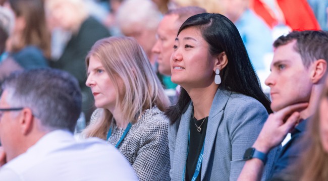 A group of diverse individuals seated around a conference table engaged in discussion in a professional setting.