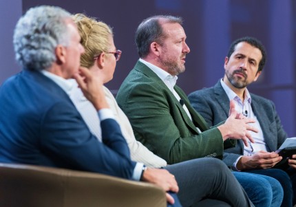 A panel of four people sitting on stage, actively conversing with each other during an event.