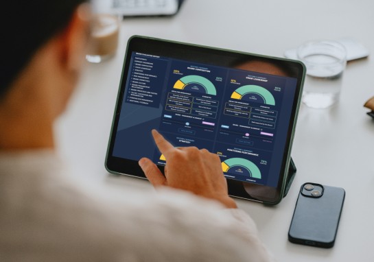 A person interacting with a tablet displaying a data dashboard, analysing information visually.