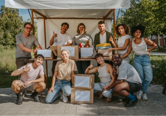Several individuals standing together in front of a food stand with boxes of goods for chairty.