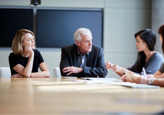 Colleagues sitting at a conference table, participating in a business meeting.