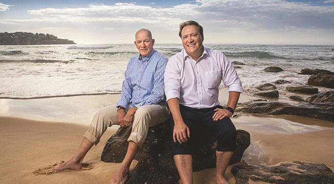 two men sat on a rock by the sea two men sat on a rock by the sea