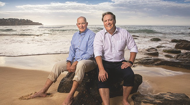 two men sat on a rock by the sea