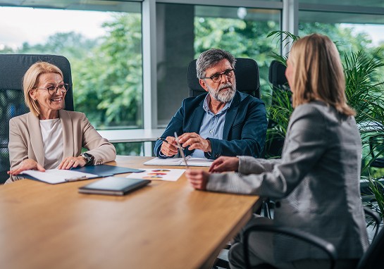 Three business professionals engaged in discussion at a conference table.