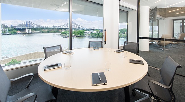 Conference room with a view of the Brisbane River, featuring a whiteboard, flipcharts, and frosted glass wall.
