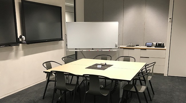 A conference room featuring a whiteboard and several chairs arranged for a meeting.