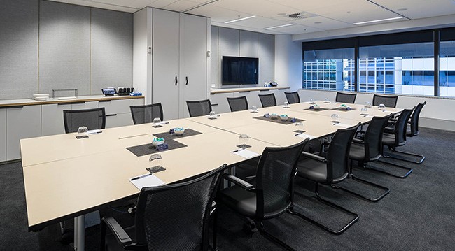 A professional conference room showcasing a long table with chairs, suitable for group discussions and presentations.