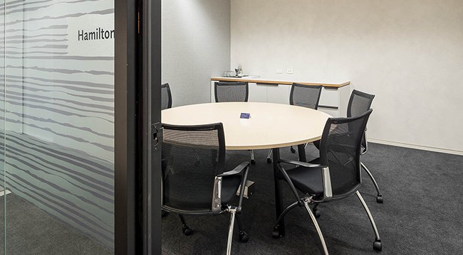 Hamilton Room: 3.4m x 4.1m boardroom for 4, equipped with a TV, whiteboard, flipcharts, and frosted glass wall.