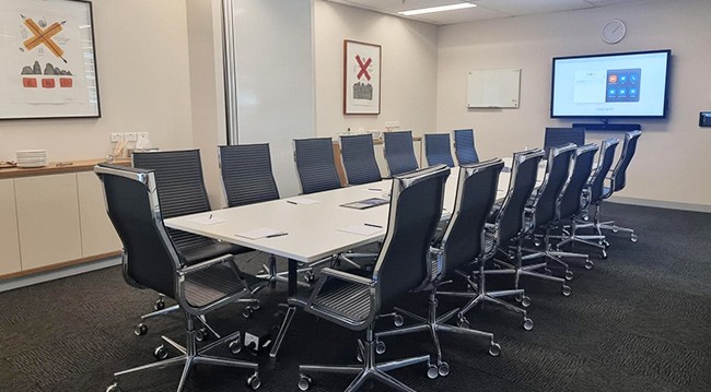 Conference room with chairs, large TV screen, whiteboard, and frosted glass wall, designed for 8 people in boardroom style.