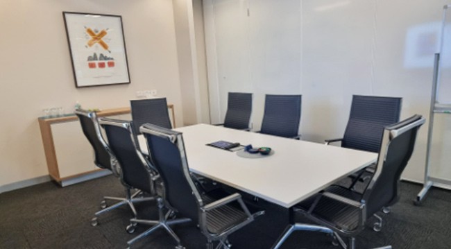A conference room featuring several chairs arranged around a whiteboard for presentations and discussions.