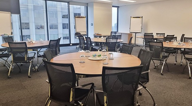 A conference room displaying tables and chairs arranged for a scheduled meeting.