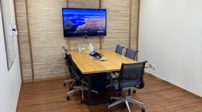 Modern conference room with a large TV, whiteboard, and flipcharts, suitable for boardroom meetings of up to 5 people.