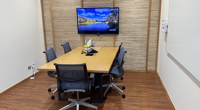 Modern conference room for 5, equipped with a large TV, whiteboard, and charging points, featuring a frosted glass wall.