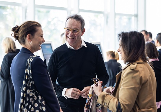 Three individuals engaged in conversation at a networking event.