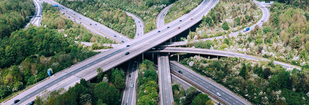 Aerial view of a highway intersection surrounded by dense forest, showcasing the road network and natural landscape.
