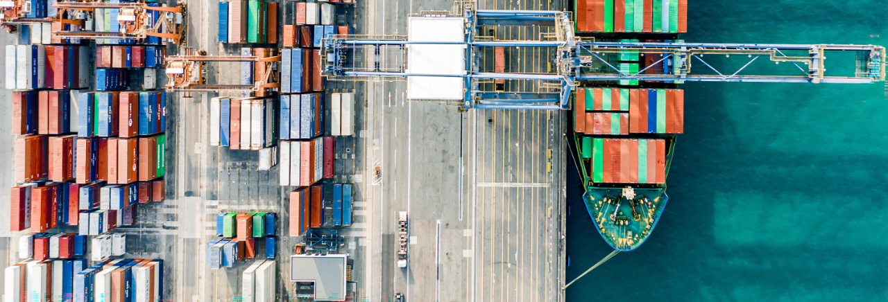 Aerial view of a large container ship surrounded by colourful cargo containers on the water.