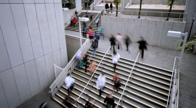 People walking up outdoor stairs in a bustling city.