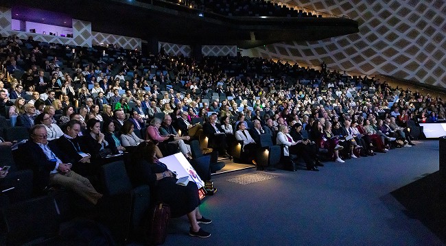 A large group of people seated attending a conference.